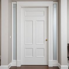 an empty room with a white door and wooden floors