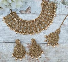 Beautiful antique gold bridal necklace jewellery set designed for a round or sweetheart neckline. Statement piece perfect for bridal wear. Comes with tikka headpiece and earrings.  Earring drop: 7 cm approx  Gold base filled with antique gold stones and ivory cream pearls. Elegant Gold Lehenga With Intricate Design, Gold Sets With Intricate Design For Reception, Gold Sets With Tilla For Reception, Gold Bridal Sets With Meenakari For Reception, Gold Temple Jewelry Sets For Reception, Gold Round Tikka For Wedding, Gold Hand-set Lehenga For Reception, Gold Wedding Tikka, Gold Hand Set Lehenga For Reception