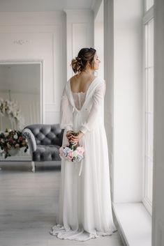 a woman in a white dress is looking out the window