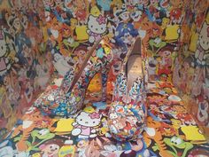 two pairs of shoes sitting on top of a multicolored cloth covered bench with cartoon characters all over it