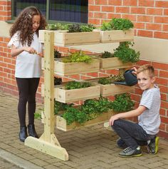 two young children are playing with an outdoor planter that is made out of wooden pallets