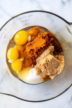 ingredients in a blender for making homemade pumpkin pie on a marble counter top, including eggs and flour