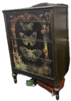 a black and gold dresser with butterflies painted on it