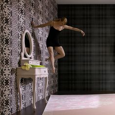 a woman in a black leotard is jumping on a table with a mirror