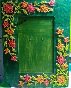 a green frame with flowers painted on the outside and inside, sitting on top of a table