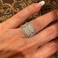 a woman's hand with a diamond ring on top of her finger and a white manicure