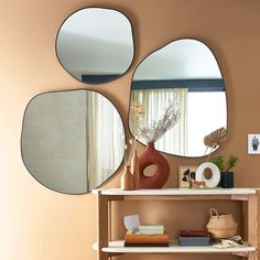 three round mirrors on the wall above a shelf with vases and other items in front of it