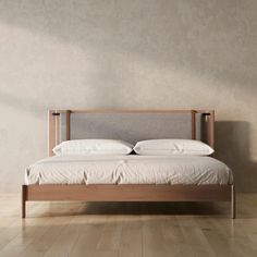 a bed with white sheets and pillows on top of it in a room that has wooden floors