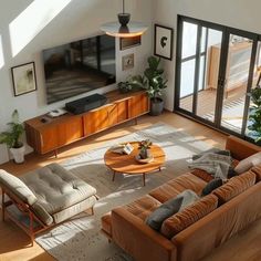 an overhead view of a living room with couches, coffee table and large windows