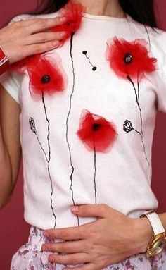 a woman with her hands on her hips wearing a white shirt with red flowers painted on it