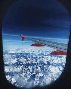 an airplane wing flying over snow covered mountains