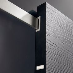 a close up view of the door handle on a black and silver door with woodgrain