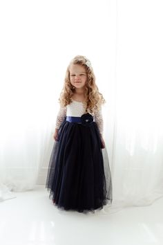 "This dress is just beautiful! It includes a delicate white lace bodice with a navy blue colored tulle skirt. The V Back with unfinished lace adds the perfect amount of boho chic look to this amazing dress. The lace sleeves are finished with the perfect amount of detail. It also includes a single flower sash that is removable. Perfect for your next special event. Nicolette's Couture is a family owned boutique based out of Dubuque, Iowa. We've had amazing success so far and believe our story is j Young Bridesmaid Dresses Navy, Navy Blue Dress For Kids, Dusty Blue Flower Girl Dress Boho, Navy Blue Flower Girl Dresses, Navy Blue Toddler Dress, Flower Girl Dresses Navy, Lace Flower Girl Dress, Dubuque Iowa, Long Sleeve Ball Gowns