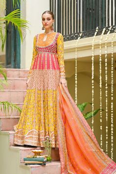 Multicolored Khaadi Silk Pishwas with Jamawar Bodice. Discover Anarkali dresses, Pishwas suits, Pakistani and Bollywood-inspired designs, embroidered frocks, gowns, and traditional attire for a stunning look. Latest trends in ethnic fashion, festive Anarkali outfits, and elegant Pishwas dresses online.Celebrate the vibrant hues of love with this stunning printed khaddi silk pishwas, a kaleidoscope of contrasting shades including Orange, Red, Pink, Peach, and Yellow. The self jamawar bodice, delicately laced with gota work, adds an element of richness to this bridal ensemble. Ideal for a daytime mehndi look, this outfit promises to be a vision of radiance and joy.The full-sleeved pishwas, adorned with a keyhole neckline, captures the essence of Anarkali dresses, embodying the grace and char Yellow Slub Silk Dupatta With Dabka Work, Orange Anarkali Set With Dupatta, Unstitched Orange Anarkali Set For Festive Occasions, Slub Silk Anarkali Set With Intricate Embroidery, Orange Bollywood Salwar Kameez For Seasonal Wear, Transitional Bollywood Style Orange Salwar Kameez, Yellow Sheer Dupatta In Slub Silk, Yellow Sheer Slub Silk Dupatta, Unstitched Orange Bollywood Anarkali Set