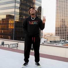 a man standing on top of a roof with his hand up in front of him