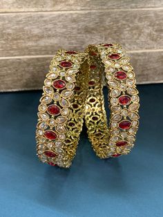 Elevate your accessory game with our Sukhi polki bangle in multi. Featuring colored Monalisa polki stones, this antique-based kada is a statement piece that adds a touch of elegance to any outfit. Made of brass and measuring approximately one inch in width, this piece is a must-have for any jewelry collection. Red Hand Set Bangle For Festivals, Hand Set Red Bangle For Festivals, Traditional Ruby Bangle For Festive Occasions, Festive Ruby Jeweled Bracelets, Festive Jeweled Ruby Bracelets, Elegant Red Tilla Bangle, Traditional Red Stone Work Bracelet, Red Bollywood Bracelets For Wedding, Bollywood Style Celebration Bangle Hand Set