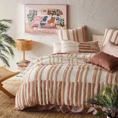 a bed with pink and white striped comforter next to a potted plant