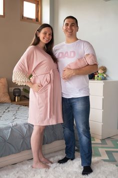 a man and woman standing next to each other in front of a bed with white carpet