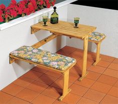 a wooden table with two benches next to it and red flowers in the window sill