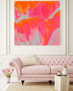 a pink couch sitting in front of a painting on the wall above it's head