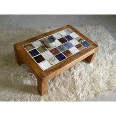 a coffee table made out of tiles on top of a white rug with a wooden frame