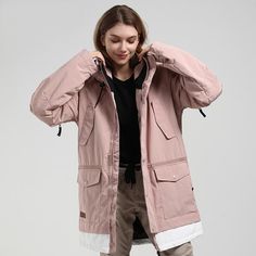 a woman in a pink parka and khaki pants is posing for the camera