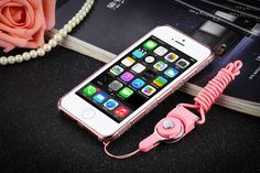 an iphone is plugged in to a pink charger on a table next to pearls