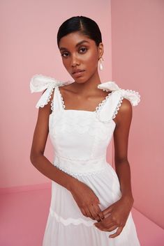 a woman in a white dress posing for the camera with her hand on her hip