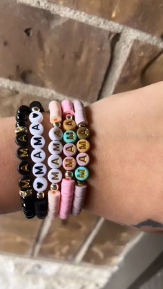 a woman's arm with four bracelets that have letters on them and beads