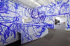 an art installation with blue spray paint on the walls and white wall in the background