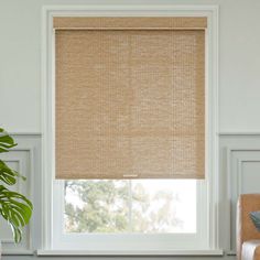 a living room with white walls and a window covered in beige roman blind shades that are hung on the windowsill