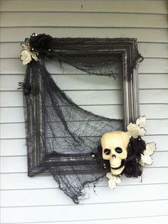 a skeleton head hanging on the side of a wall next to a black net frame