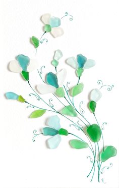 some green and white glass flowers on a white background with watercolor paper in the shape of leaves