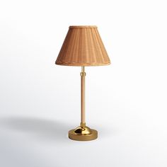 a lamp that is on top of a white surface with a gold base and shade