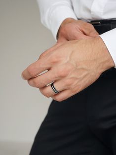 a man in a white shirt and black pants is wearing a wedding band on his ring