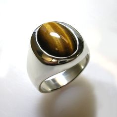 Masculine elegance. A truly stunning ring. Our own unique spin on a smart looking, timeless classic. We use finest quality, rare, Tiger Eye in a specially cut high dome that shows more stone which creates a unique and striking effect. This ring is solid- not hollowed out underneath which gives it a substantial value and weight and nicer feel and weighs from approx. 24 to 30 grams depending on the ring size. Truly looks great on a a wide range of finger sizes. (pictured on a size 10 ring finger) Luxury Oval Cabochon Gemstones For Anniversary, Modern Oval Sterling Silver Signet Ring, Formal Oval Signet Ring With Polished Edges, Modern Oval Cabochon Signet Ring For Formal Occasions, Timeless Cabochon Rings For Formal Occasions, Classic Round Cabochon Gemstones, Modern Oval White Gold Signet Ring, Luxury Oval Cabochon Gemstones, Modern Oval Cabochon Signet Ring For Gift