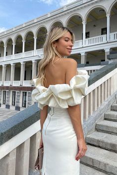 a woman in a white dress standing on some steps