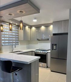 a modern kitchen with stainless steel appliances and white counter tops, along with two bar stools