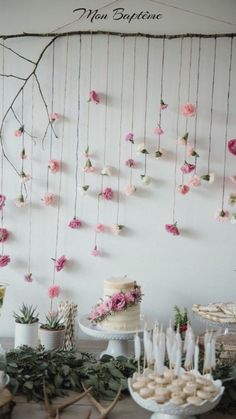 a table topped with cakes and desserts under a hanging flower decoration on the wall