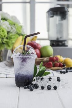 an iced drink with blueberries and lemons on the table next to fresh fruit