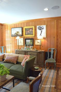 a living room filled with furniture and wooden paneled walls, along with pictures on the wall