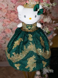 a hello kitty doll in a green dress with gold sequins and a tiara