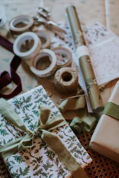 wrapping presents on a table with ribbon and spools of thread next to them