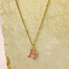 Add a touch of personality and whimsy to your look with our Personalized Pink Initial Necklace. This charming necklace features a custom letter of your choice, crafted with a gold-plated finish and filled with vibrant pink enamel. The delicate chain complements the playful letter, creating a cheerful and eye-catching piece. Perfect for everyday wear or as a gift, this necklace is a delightful way to express your unique style. Personalized Enamel Charm Necklaces For Gifts, Personalized Gold Enamel Charm Necklace, Pink Pendant Charm Necklace, Pink Necklace With Adjustable Chain As A Gift, Enamel Initial Pendant Jewelry Gift, Pink Name Necklace For Valentine's Day Gift, Personalized Pink Charm Necklace As Gift, Pink Pendant Charm Necklace For Birthday, Pink Necklace With Adjustable Chain For Her