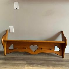 a wooden shelf with hearts cut out of the top and two lights on each side