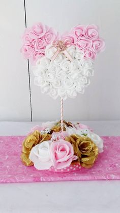 a pink and white heart shaped cake with flowers on it's top, sitting on a pink table cloth