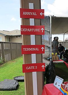 several signs pointing in different directions at an outdoor event with people standing around the tent