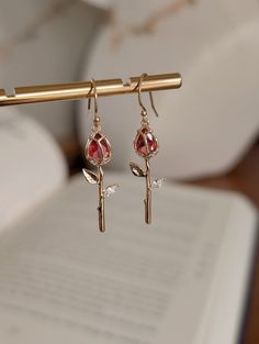 DAINTY RED ROSE DANGLE EARRINGS  A stunning pair of gold drop earrings with a single stem gold red rose  DETAILS  *Petite drop earrings, minimal but stylish. *Length of drop 3cm from the charm. *Ear wires are gold filled.  *Your earrings will arrive safely packaged in a jewelry gift bag Please note - earrings are none returnable due to hygiene reasons. DELIVERY DEATAILS* *All UK orders are sent via the Royal Mail 1st Class Signed for service. *All international orders are sent via a Tracked and Rose Gold Flower Earrings For Valentine's Day, Rose Gold Flower-shaped Earrings For Valentine's Day, Elegant Gold Crystal Earrings For Valentine's Day, Valentine's Day Rose Gold Flower Earrings, Rose Gold Crystal Earrings For Pierced Ears As Gift, Rose Gold Crystal Earrings As A Gift, Rose Gold Earrings With Rose Flower Design, Rose Gold Single Flower-shaped Earring, Rose Earrings For Valentine's Day