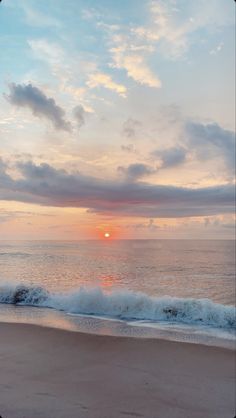 the sun is setting over the ocean with waves crashing on the shore and clouds in the sky