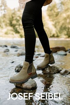 Woman with black jeans wears olive colored Chelsea pull-on boots as she scales rocks in a stream. Rugged Chelsea Ankle Boots For Outdoor, Winter Outdoor Boots With Leather Footbed, Rugged Chelsea Boots For Outdoor Fall Activities, Rugged Waterproof Slip-on Boots With Vibram Sole, Rugged Chelsea Boots For Winter Outdoor, Winter Chelsea Boots With Reinforced Toe For Outdoor, Rugged Chelsea Boots With Reinforced Toe For Outdoor, Medium Width Round Toe Boots For Outdoor, Ankle-high Chelsea Boots For Fall Outdoor